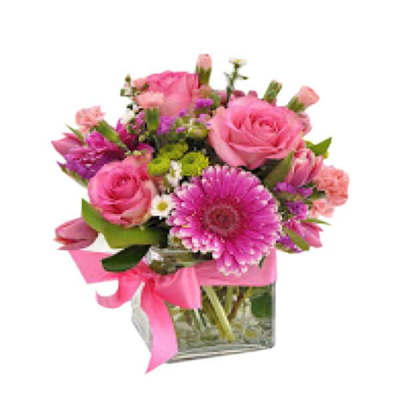 Pink roses and gerbera daisies in a glass vase with a pink ribbon