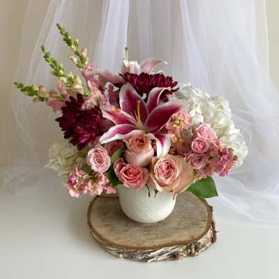 Pink and white floral arrangement in a white vase with lilies and roses