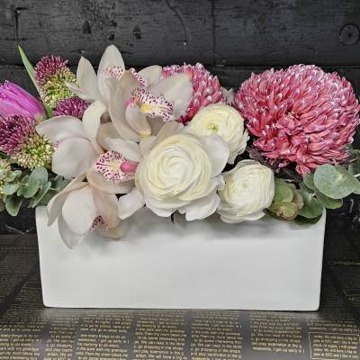 Pink and white floral arrangement in a white rectangular vase