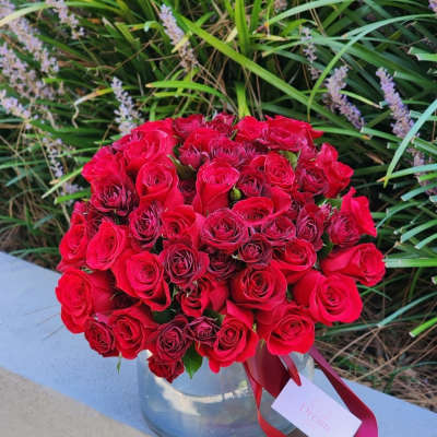Bouquet of red roses in a clear glass vase with a ribbon tag