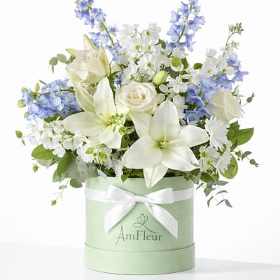 White lilies and roses with blue flowers in a mint green hat box