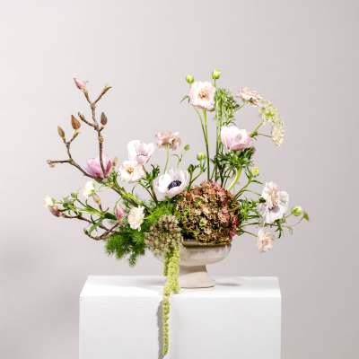 Pastel floral arrangement in a pedestal vase with branching stems