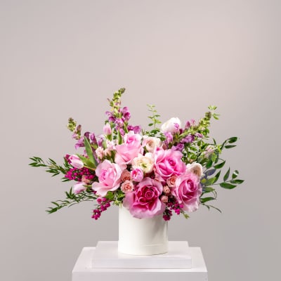 Pink and white roses arranged in a white cylindrical vase