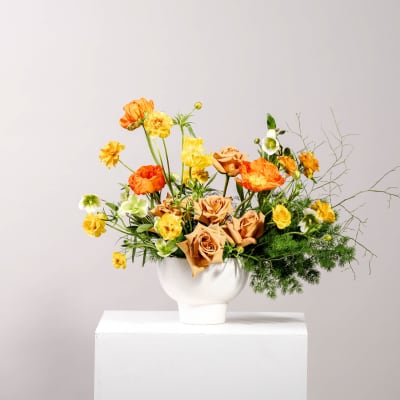 Orange and yellow flowers arranged in a white vase