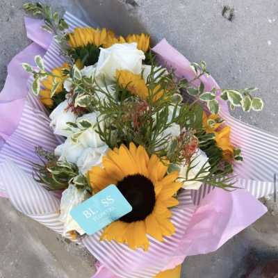 Bouquet of sunflowers and white roses wrapped in pink paper