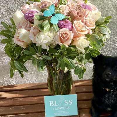 Pink and white rose bouquet in a glass vase with a blue butterfly decoration