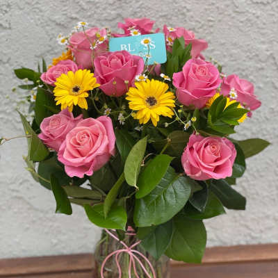 Pink roses and yellow daisies in a clear glass vase