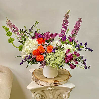 Colorful flower arrangement in a white vase on a wooden slab