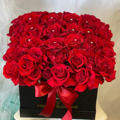 Red roses arranged in a black box with a satin ribbon