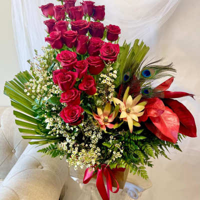 Tall bouquet of red roses with tropical accents and a red ribbon
