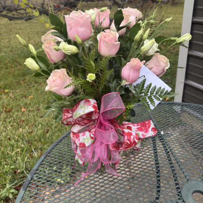 Pink roses arranged in a clear vase with pink ribbon
