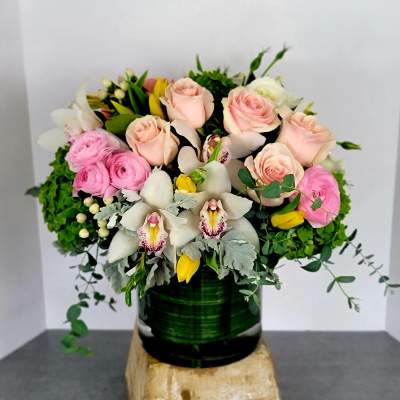 Pink roses and white orchids in a dark green vase