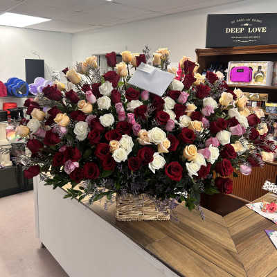Large basket arrangement of red, white, pink, and peach roses