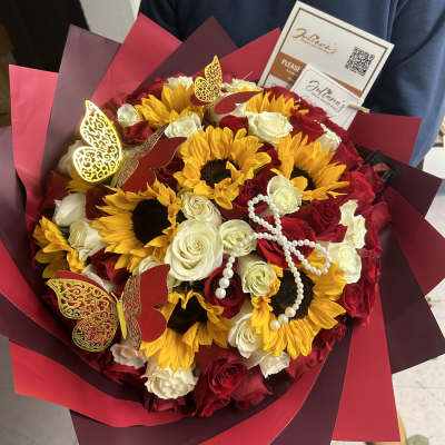 Bouquet of red and white roses with sunflowers in burgundy wrap