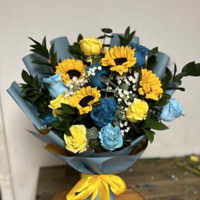 Bouquet of yellow sunflowers and blue and yellow roses wrapped in blue paper