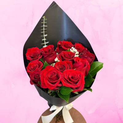 Bouquet of red roses wrapped in black paper with a white ribbon