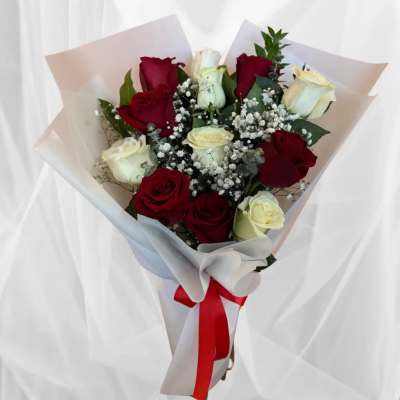 Bouquet of red and white roses wrapped in pale paper with a red ribbon