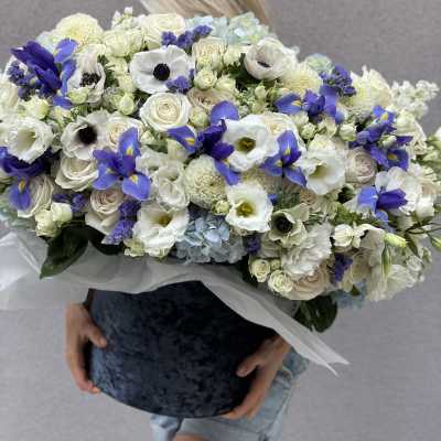 Large bouquet of white and blue flowers held in front of a person