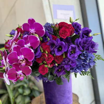 Purple and pink bouquet with orchids, roses, and hydrangeas in a purple vase