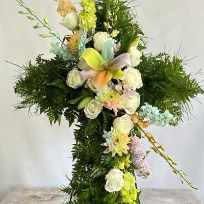 Cross-shaped floral tribute with white roses and pastel blooms