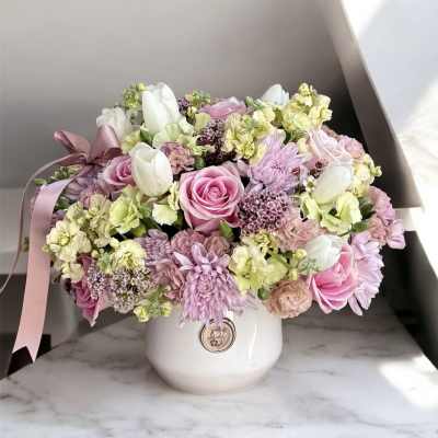 Pink and white mixed flower arrangement in a white vase with a ribbon