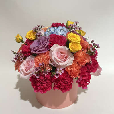 Colorful bouquet of roses, carnations, and hydrangea in a pink box