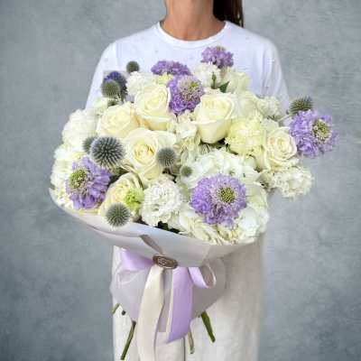 Large bouquet of white roses and lavender flowers wrapped in pale paper