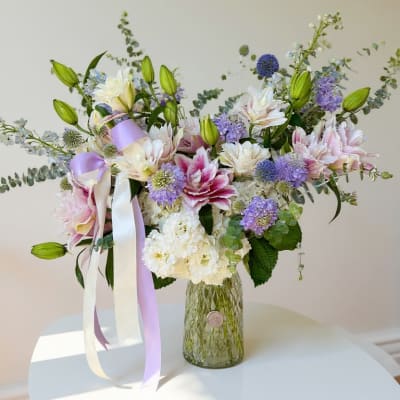 Pastel bouquet in a glass vase with lilies and ribbon streamers