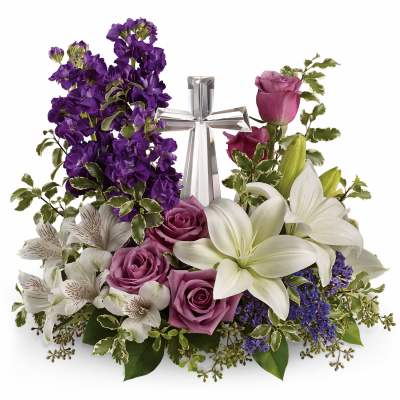 Purple and white floral arrangement with roses, lilies, and a silver cross