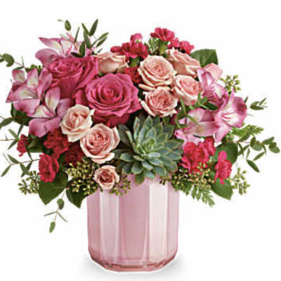 Pink and peach roses in a pink glass vase with greenery