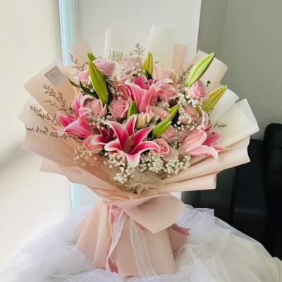 Pink lilies and roses bouquet wrapped in blush paper