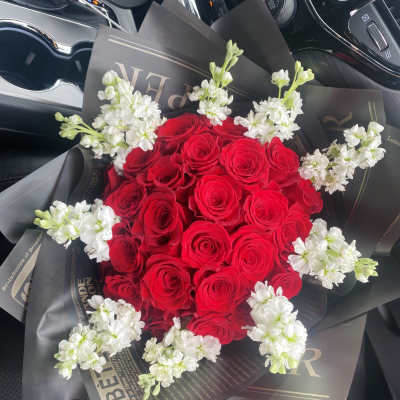 Bouquet of red roses with white accent flowers in black wrap