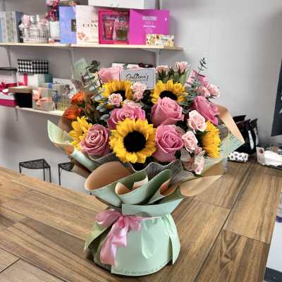 Bouquet of pink roses and sunflowers wrapped in pastel paper
