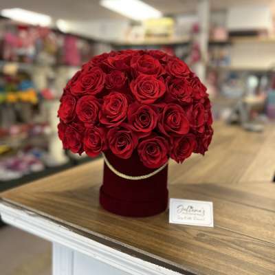 Round bouquet of red roses in a burgundy hat box