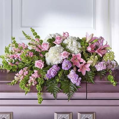 Pink and white floral casket spray with lilies, roses, and hydrangeas