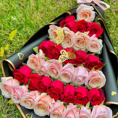Bouquet of red and blush roses wrapped in black paper with gold trim
