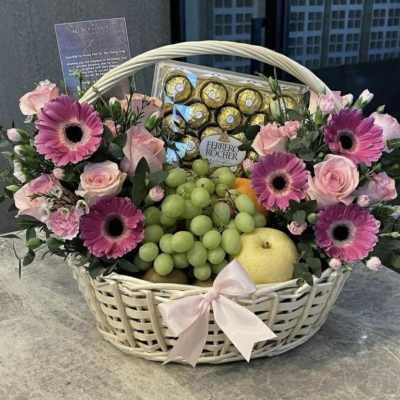 Flower and fruit basket with pink gerberas, roses, grapes, and chocolates
