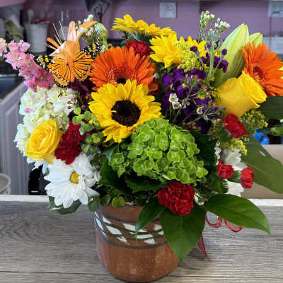 Bright mixed bouquet in a ceramic vase with a butterfly decoration