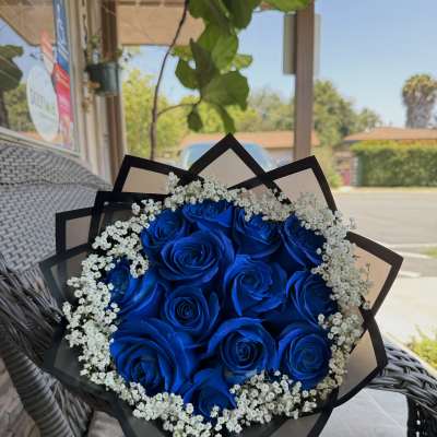 Bouquet of vivid blue roses with white baby's breath in black wrap