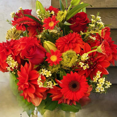 Red gerbera daisies and roses in a glass vase