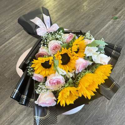 Bouquet of sunflowers and pink roses wrapped in black paper
