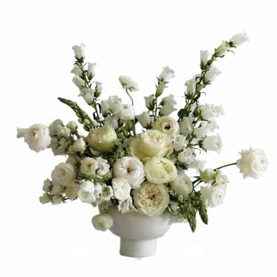 Low white compote arrangement of ivory roses and ranunculus with airy white accent flowers
