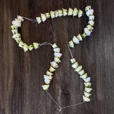 White rose floral garland arranged in a looping shape on a dark wood surface