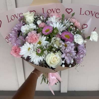 Pink and white mixed bouquet wrapped in paper with a satin ribbon