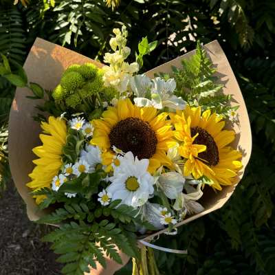 Bouquet of sunflowers, white daisies, and green chrysanthemums wrapped in brown paper