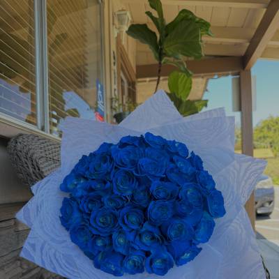Bouquet of vivid blue roses wrapped in white paper
