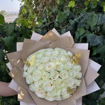 Bouquet of white roses wrapped in tan paper with gold butterfly accents