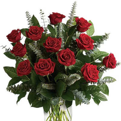Red roses arranged in a clear glass vase with greenery