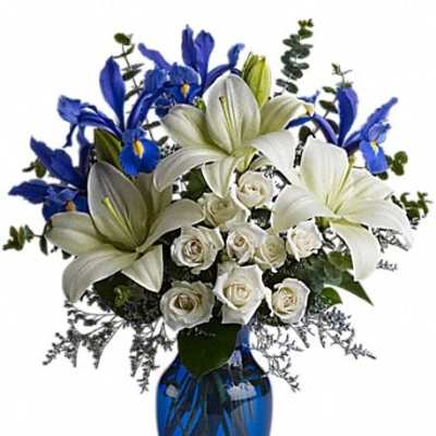 White lilies and roses arranged in a blue vase with blue iris accents