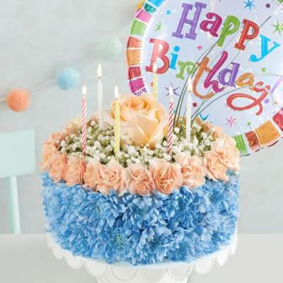 Birthday cake decorated with flowers and candles, topped with a birthday balloon